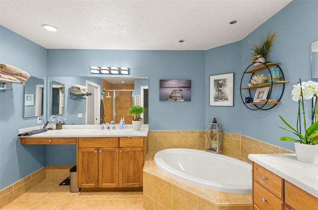 bathroom with a textured ceiling, tile floors, vanity, and tiled bath