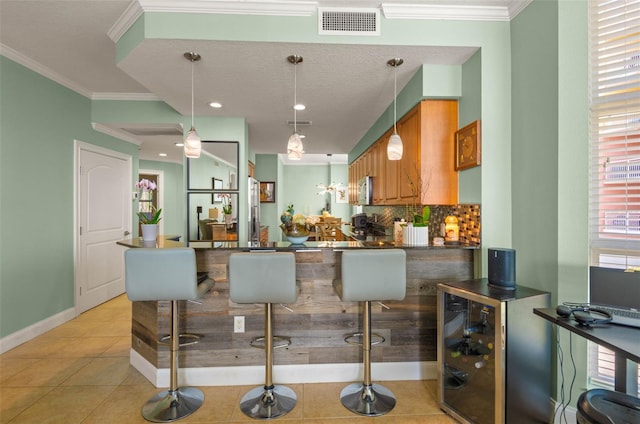 kitchen featuring kitchen peninsula, light tile floors, crown molding, and a breakfast bar