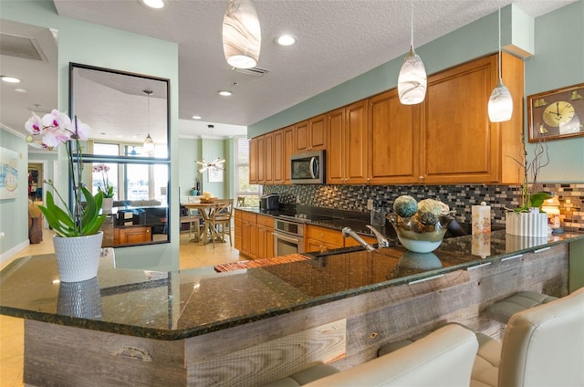 kitchen with decorative light fixtures, appliances with stainless steel finishes, backsplash, light tile flooring, and sink