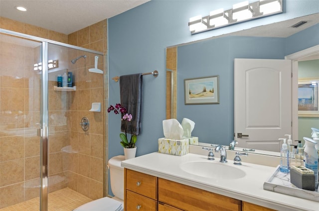 bathroom with a shower with shower door, toilet, and vanity