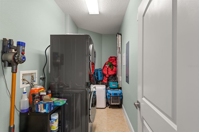 laundry room featuring hookup for a washing machine, stacked washer / dryer, a textured ceiling, and light tile flooring