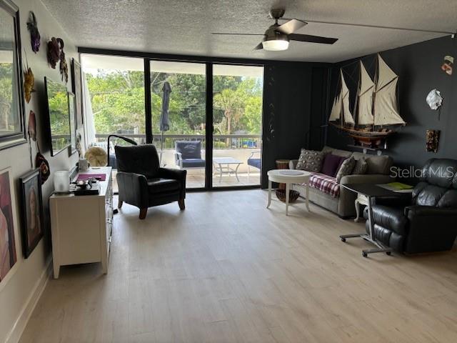 living room featuring wood-type flooring, ceiling fan, and a textured ceiling