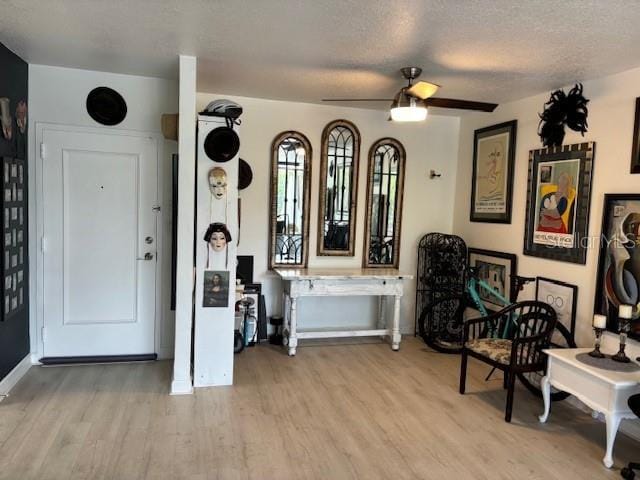 interior space featuring ceiling fan, light wood-type flooring, and a textured ceiling