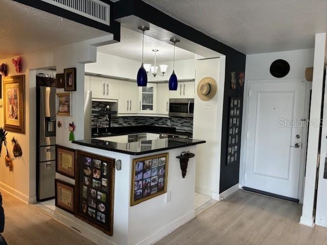 kitchen featuring kitchen peninsula, stainless steel appliances, light hardwood / wood-style floors, and white cabinetry