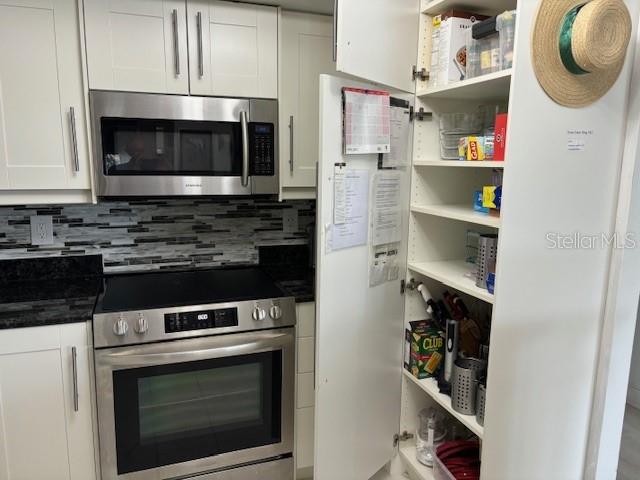 kitchen with white cabinets, tasteful backsplash, white refrigerator, and range