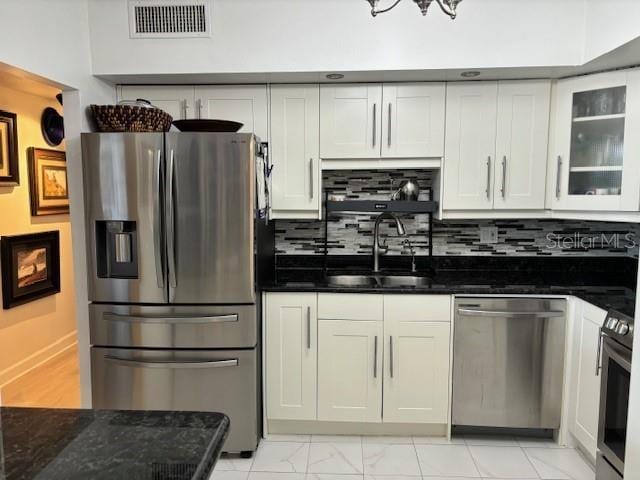 kitchen with backsplash, stainless steel appliances, white cabinets, sink, and light tile floors