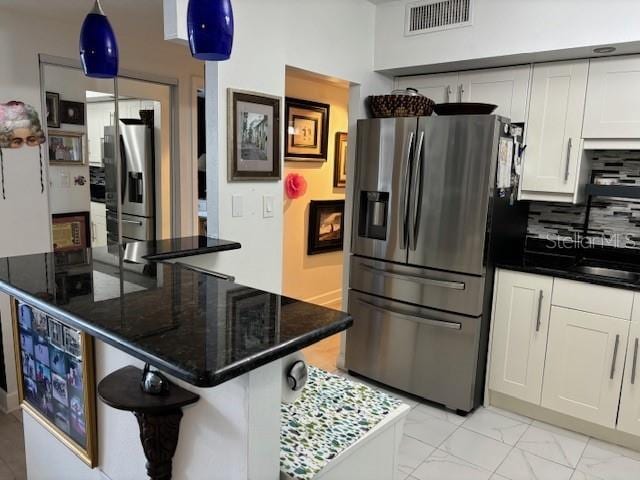 kitchen featuring stainless steel fridge with ice dispenser, tasteful backsplash, white cabinetry, and pendant lighting