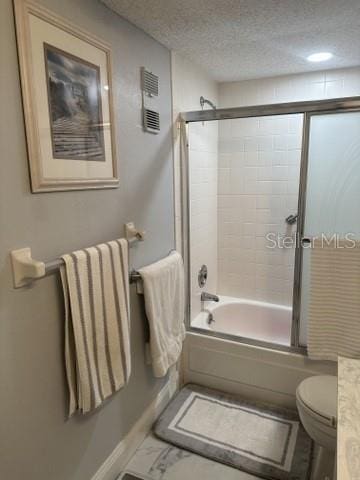 bathroom with enclosed tub / shower combo, a textured ceiling, and toilet