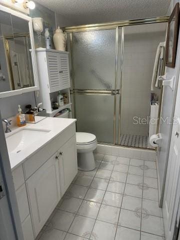 bathroom featuring vanity, tile patterned flooring, toilet, and an enclosed shower