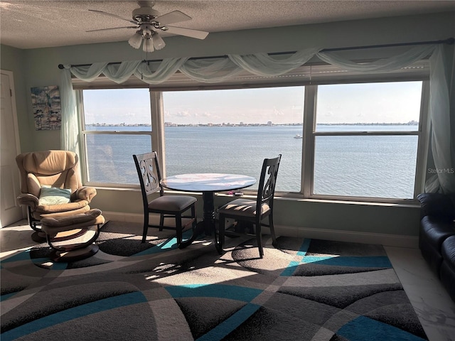 dining space featuring a textured ceiling, a water view, and ceiling fan