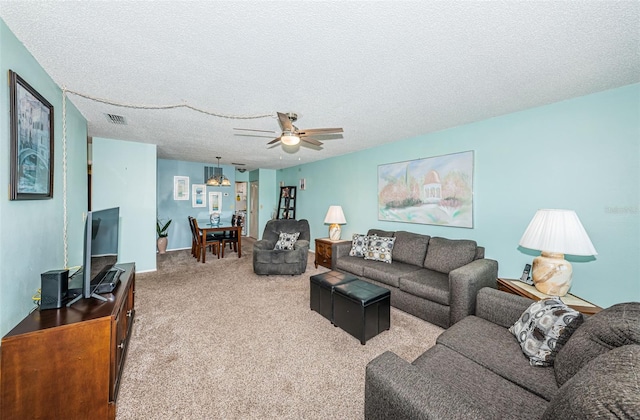 living room featuring a textured ceiling, carpet floors, and ceiling fan