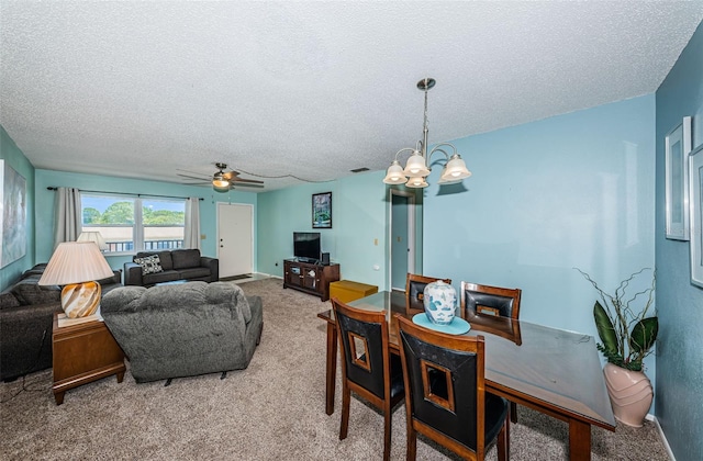 carpeted dining space featuring ceiling fan with notable chandelier and a textured ceiling