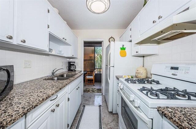 kitchen featuring white cabinets, light tile flooring, white gas stove, backsplash, and sink