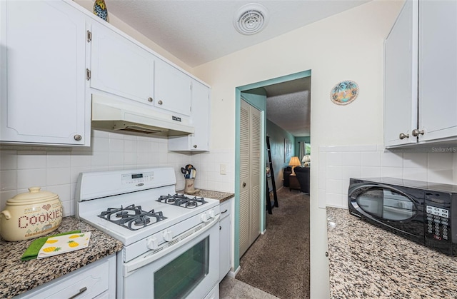 kitchen with white cabinets, tasteful backsplash, white gas range oven, and dark stone counters