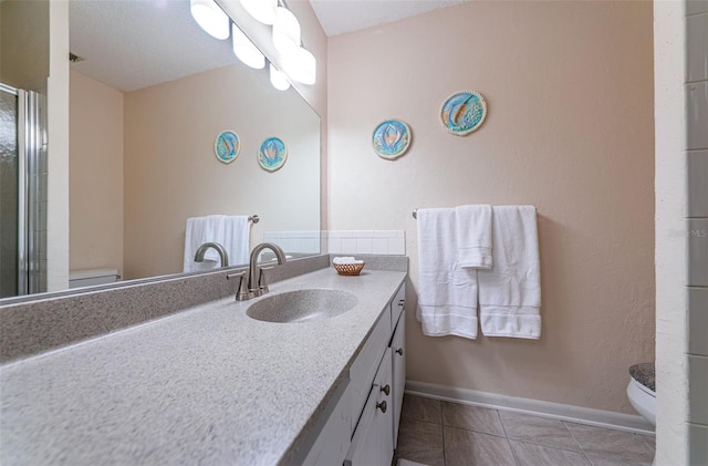 bathroom featuring tile floors, oversized vanity, toilet, and a textured ceiling