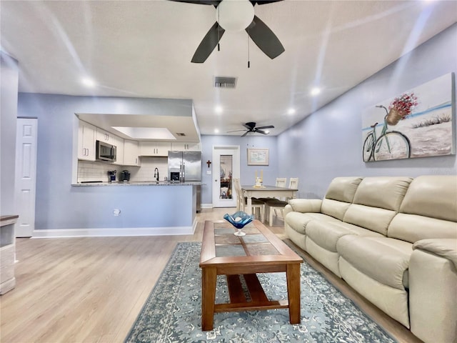 living room featuring light hardwood / wood-style flooring and ceiling fan