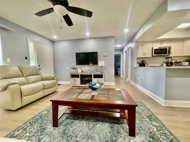 living room with light wood-type flooring and ceiling fan