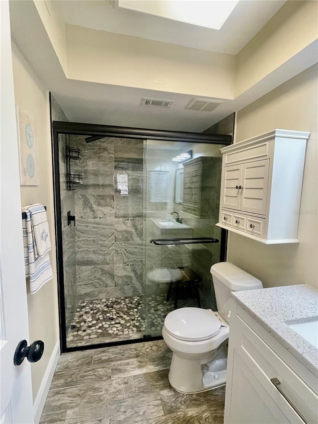 bathroom with a shower with door, vanity, and toilet