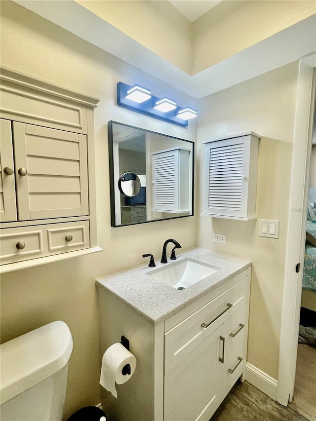 bathroom featuring toilet, hardwood / wood-style flooring, and vanity