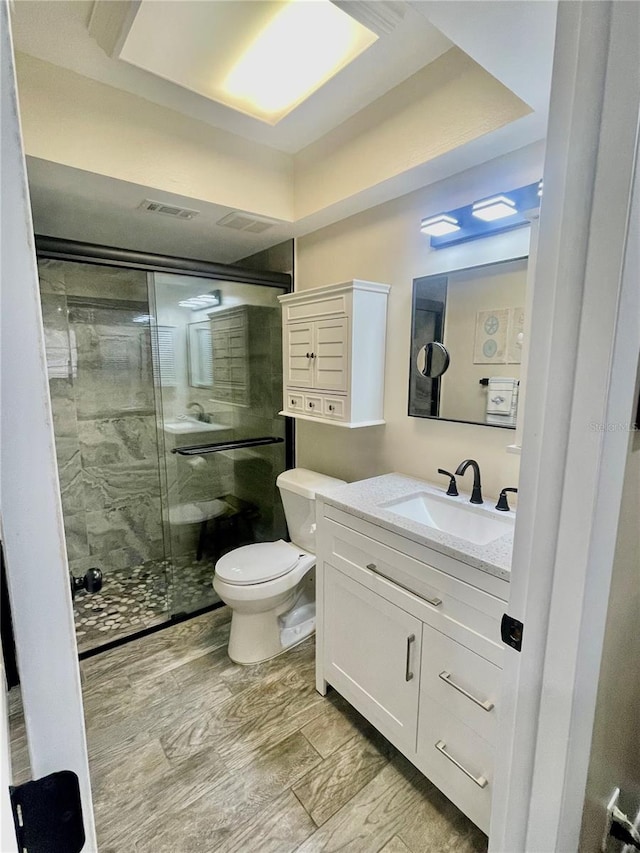 bathroom with vanity, toilet, an enclosed shower, and hardwood / wood-style floors