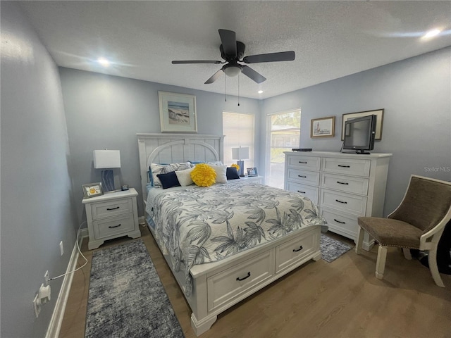 bedroom featuring ceiling fan, dark hardwood / wood-style flooring, and a textured ceiling