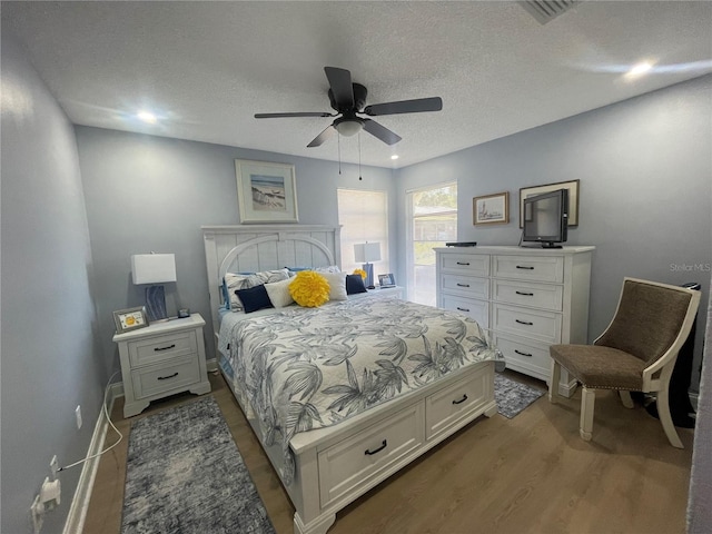 bedroom featuring a textured ceiling, dark wood-type flooring, and ceiling fan