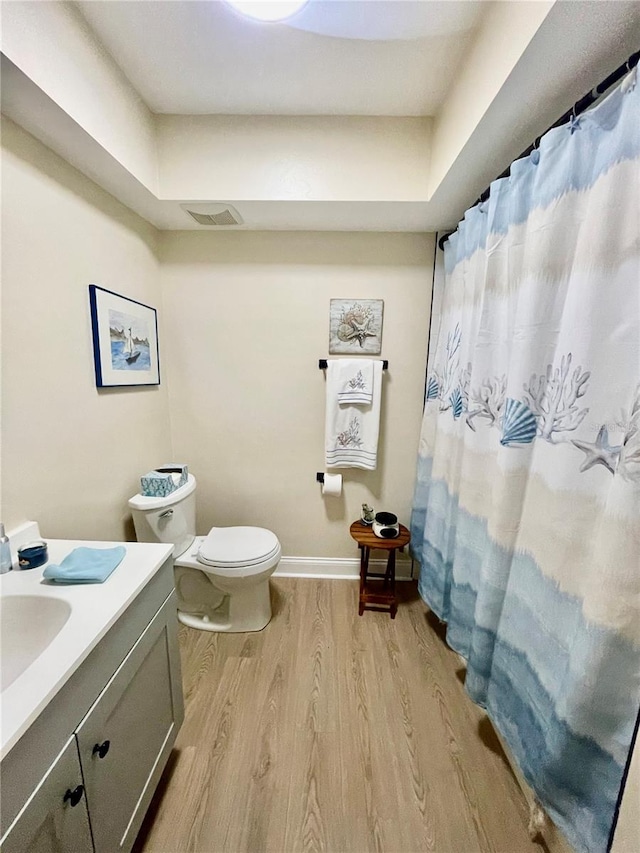 bathroom with hardwood / wood-style floors, toilet, a shower with shower curtain, and vanity