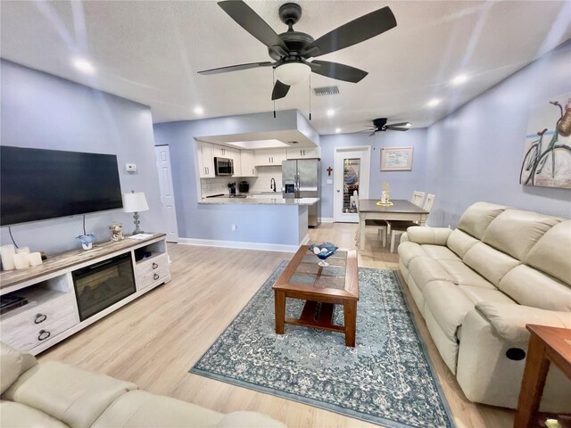 living room with ceiling fan and light hardwood / wood-style floors