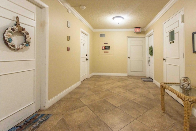 interior space featuring baseboards, a textured ceiling, visible vents, and crown molding