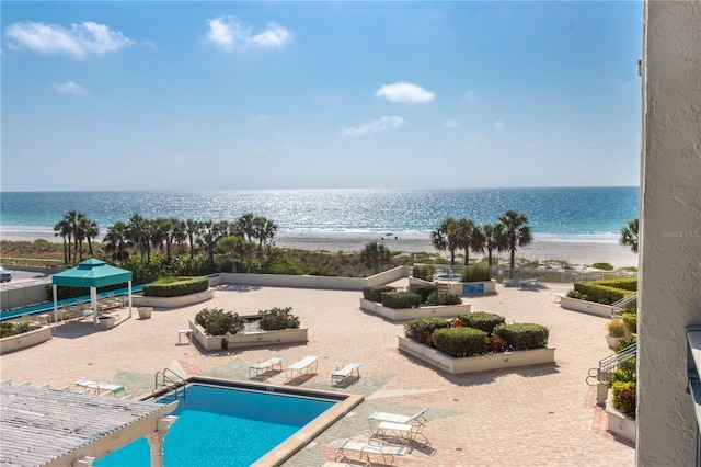 pool featuring a water view, a beach view, and a patio