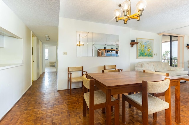 dining space with a chandelier, a textured ceiling, and baseboards