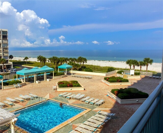 community pool with a view of the beach, a water view, a patio, and a pergola