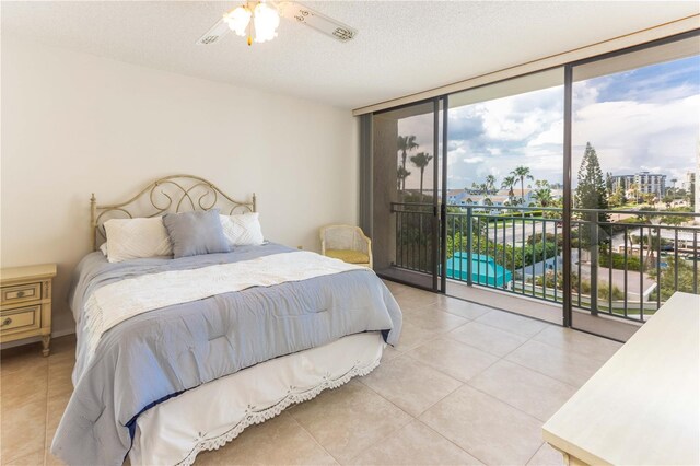 bedroom featuring light tile patterned floors, ceiling fan, access to exterior, a textured ceiling, and floor to ceiling windows