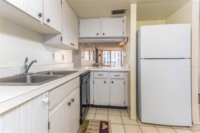 kitchen featuring visible vents, dishwasher, freestanding refrigerator, light countertops, and a sink