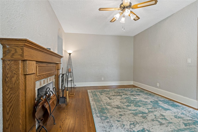 unfurnished living room featuring ceiling fan, dark hardwood / wood-style floors, and a textured ceiling