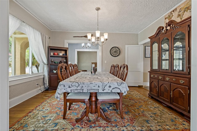 dining room featuring a textured ceiling, a notable chandelier, crown molding, and hardwood / wood-style flooring