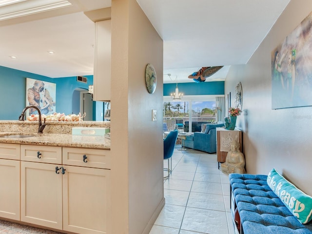 kitchen with light stone counters, a chandelier, sink, light tile floors, and pendant lighting