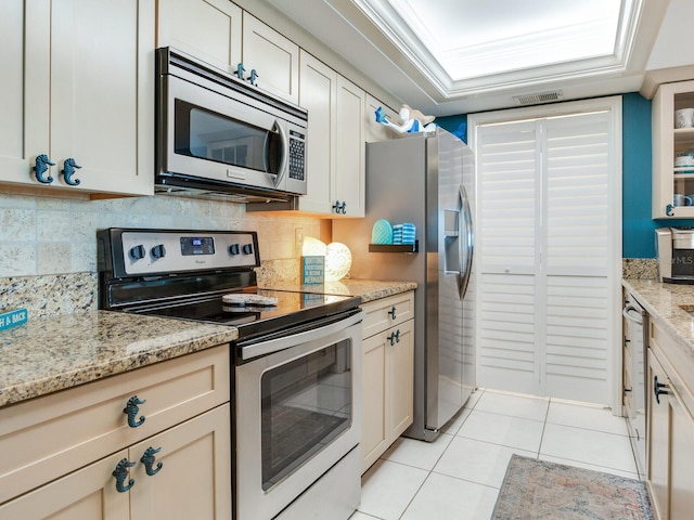 kitchen featuring backsplash, appliances with stainless steel finishes, light tile flooring, and light stone counters