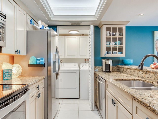 laundry area with cabinets, washing machine and clothes dryer, crown molding, sink, and light tile floors