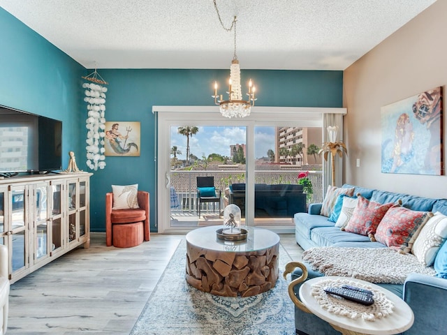 living room with a notable chandelier, a textured ceiling, and light hardwood / wood-style flooring