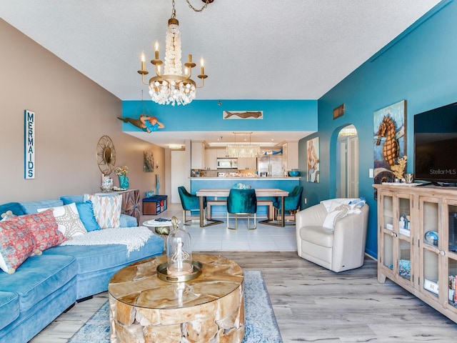 living room with a notable chandelier, light hardwood / wood-style floors, and a textured ceiling