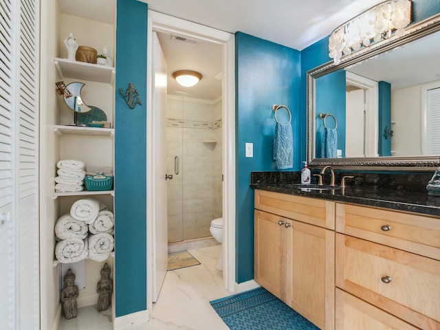 bathroom featuring a shower with door, tile flooring, vanity, and toilet