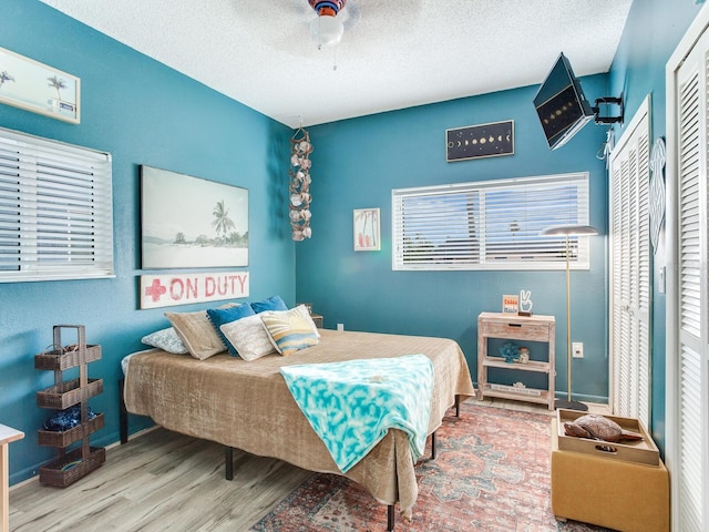 bedroom featuring ceiling fan, a closet, a textured ceiling, and wood-type flooring