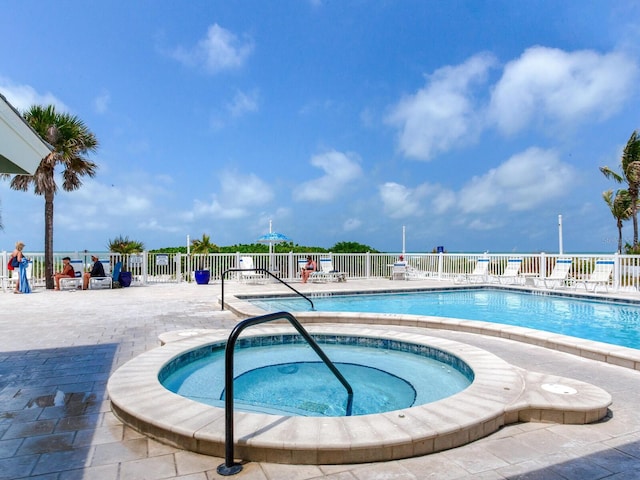 view of swimming pool featuring a hot tub and a patio