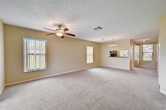 unfurnished living room featuring ceiling fan, carpet floors, a wealth of natural light, and a textured ceiling