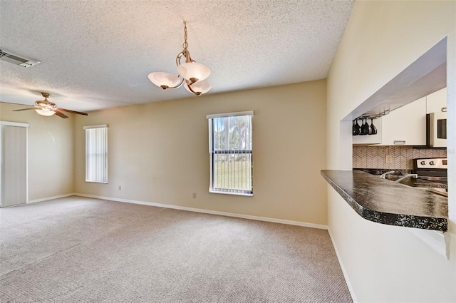 kitchen with light colored carpet, a textured ceiling, electric stove, and white cabinetry