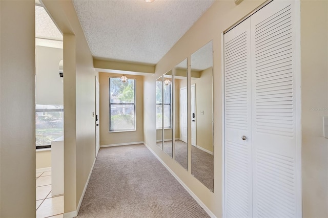 hallway featuring light colored carpet and a textured ceiling