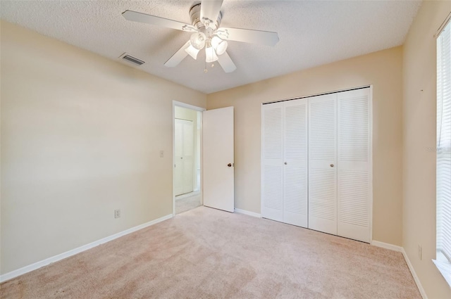 unfurnished bedroom featuring light carpet, a closet, ceiling fan, and a textured ceiling