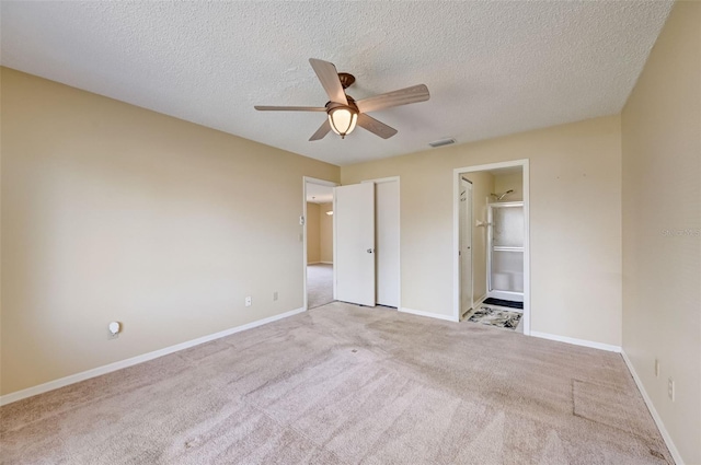 unfurnished bedroom with a spacious closet, a textured ceiling, ceiling fan, and light carpet