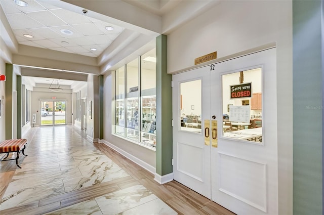 entryway featuring french doors, light tile floors, and a tray ceiling